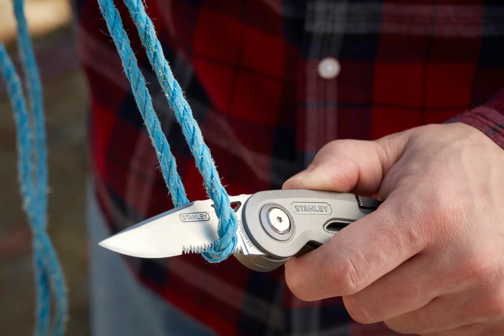 STANLEY 0-10-813 folding utility knife cutting blue rope, close-up view.