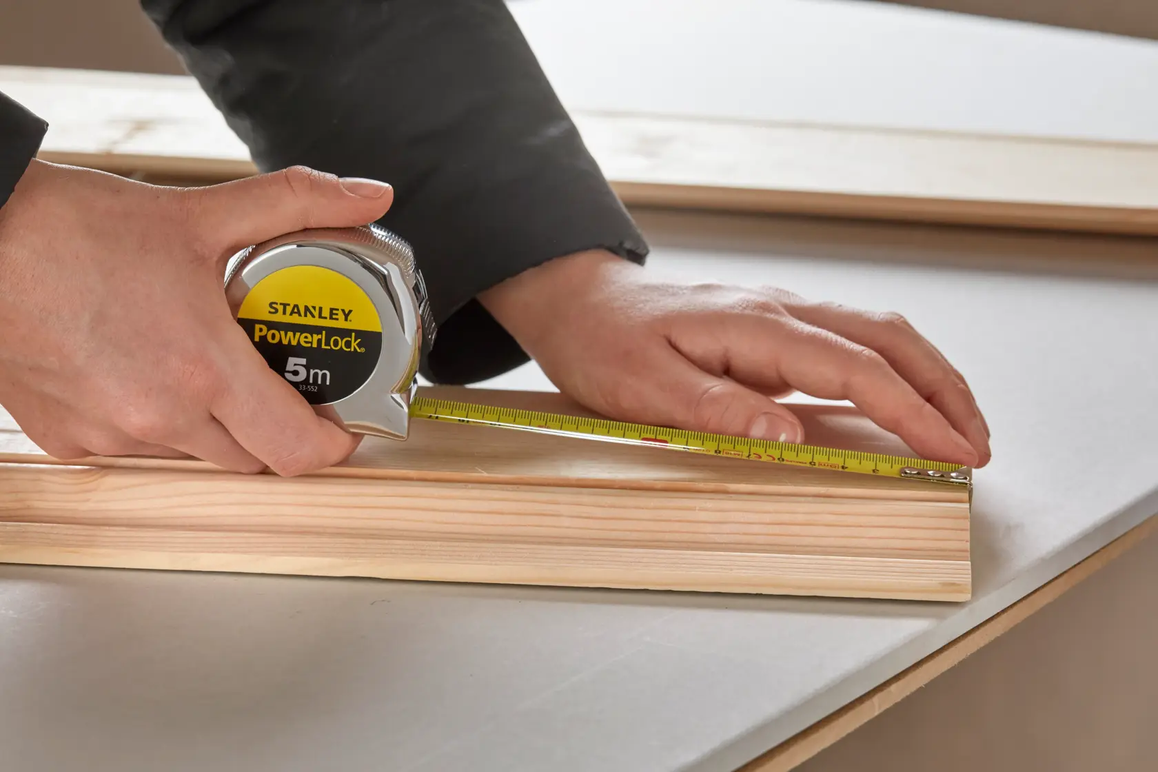 STANLEY 0-33-552 tape measure used to measure wood on tabletop, close-up photography.