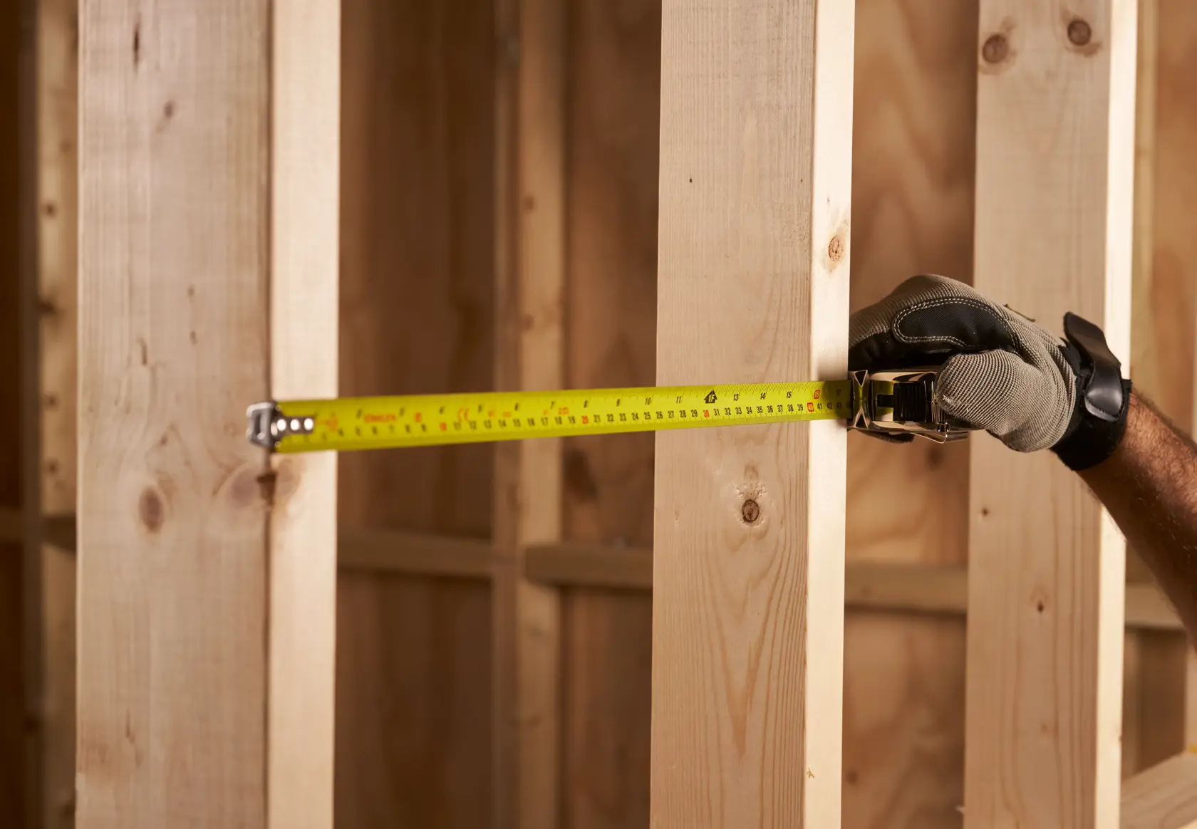 STANLEY 0-33-553 tape measure in use measuring wooden beams, side angle, yellow tape visible.
