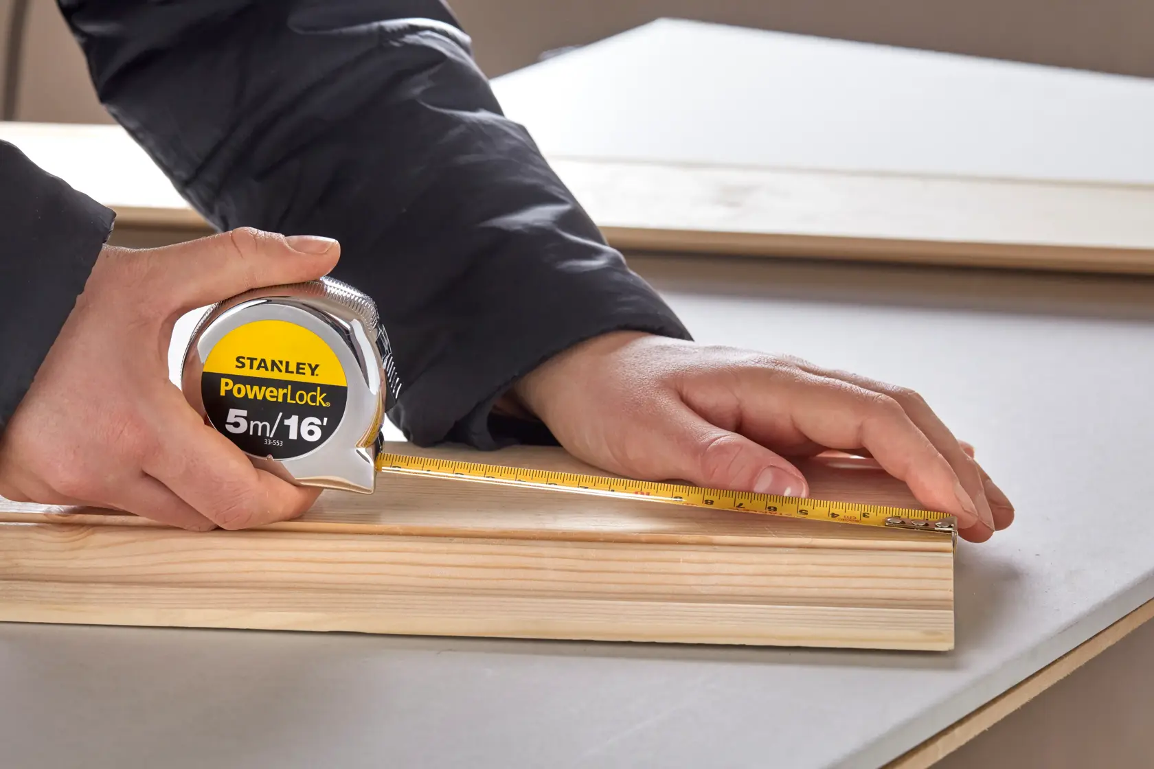 STANLEY 0-33-553 tape measure used to measure wood plank, close-up photography.