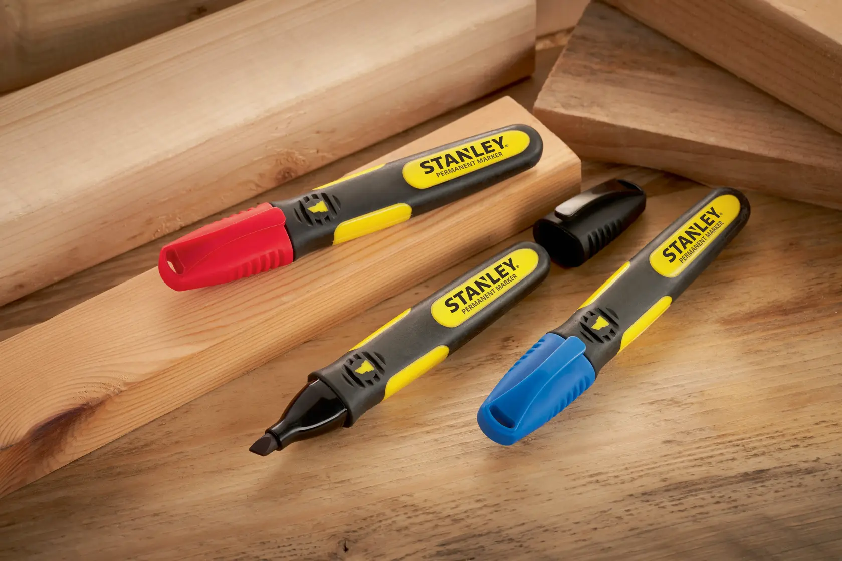 STANLEY SKU 0-47-315 permanent markers with red, blue, and black caps on wooden boards, angled view.