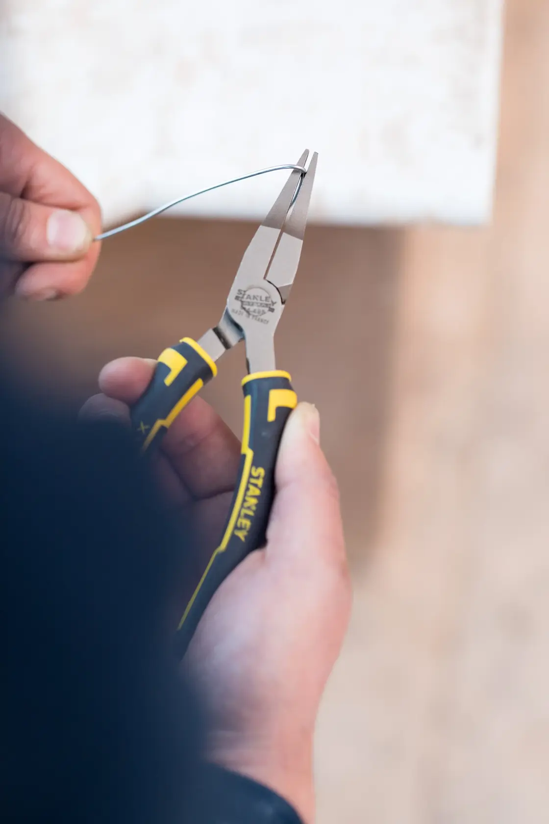 STANLEY 0-84-495 pliers with yellow and black handles in use bending wire, close-up photography.