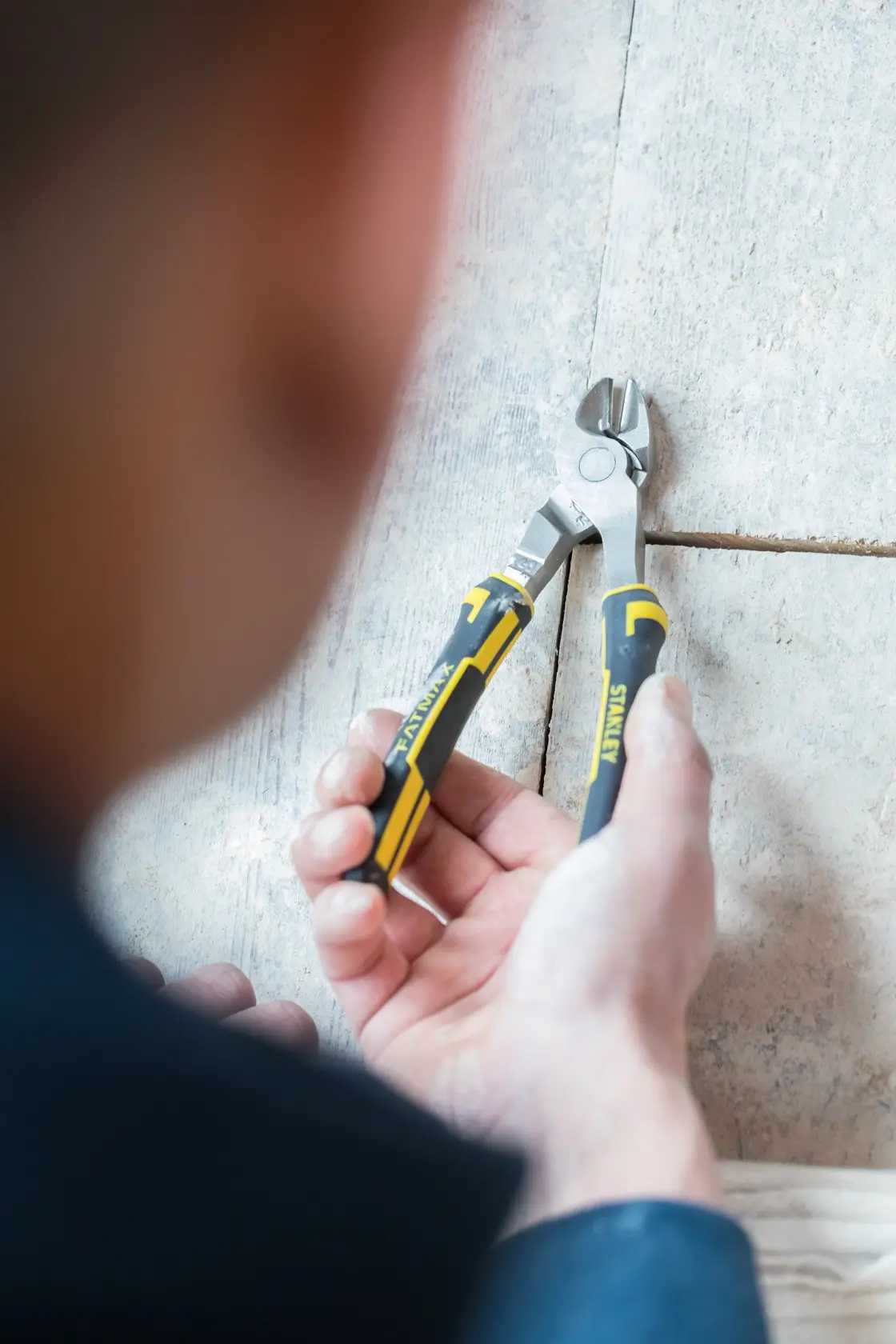 Photo of STANLEY 0-89-860 diagonal cutting pliers with black and yellow handles, held by a person on a tiled surface.