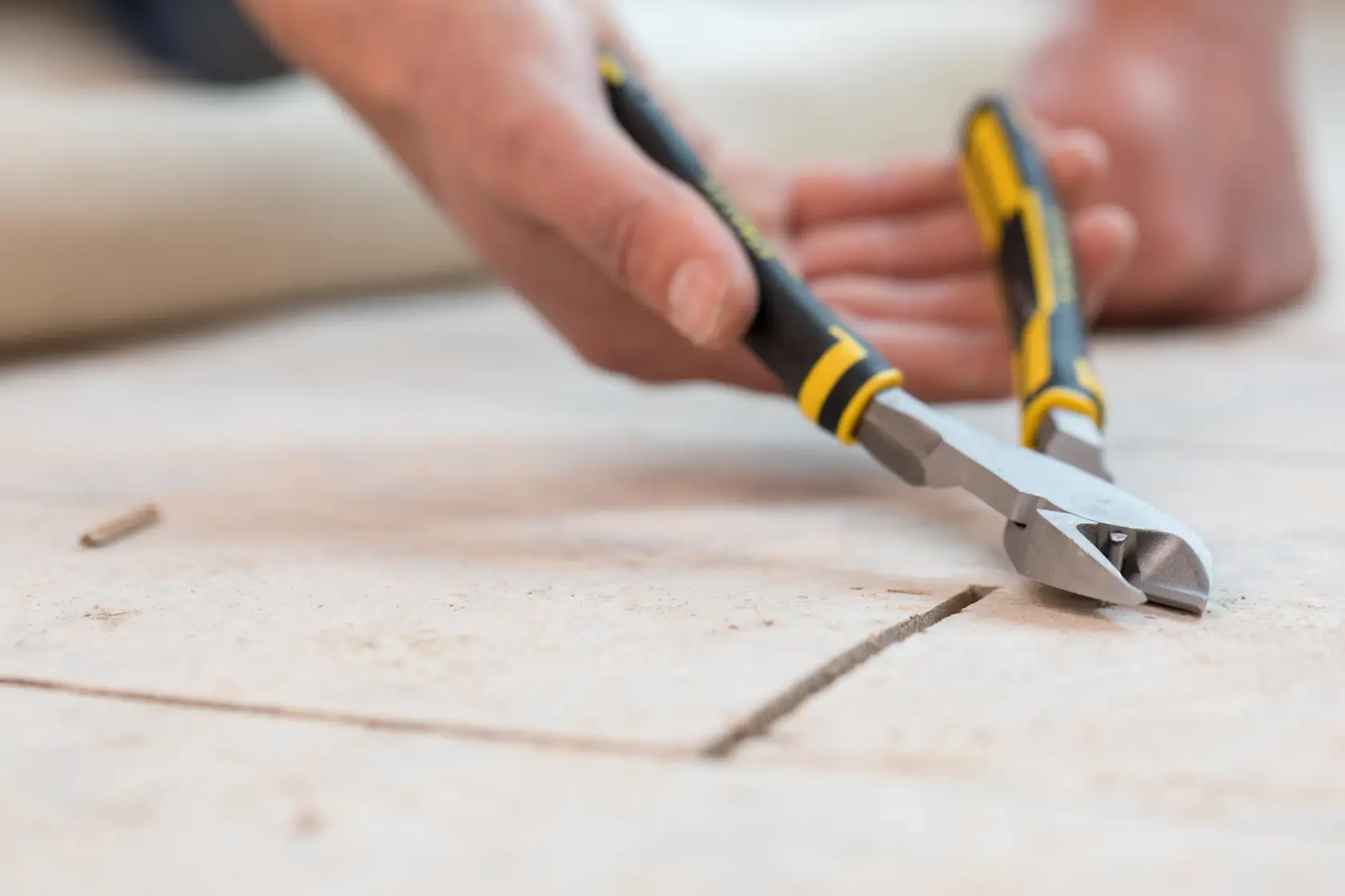 STANLEY 0-89-861 hand cutting pliers in use, black and yellow handle, close-up on tile flooring.