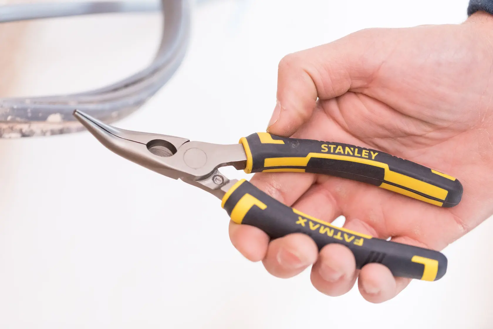 STANLEY 0-89-871 long nose pliers with black and yellow FATMAX grips, held in hand, side angle.
