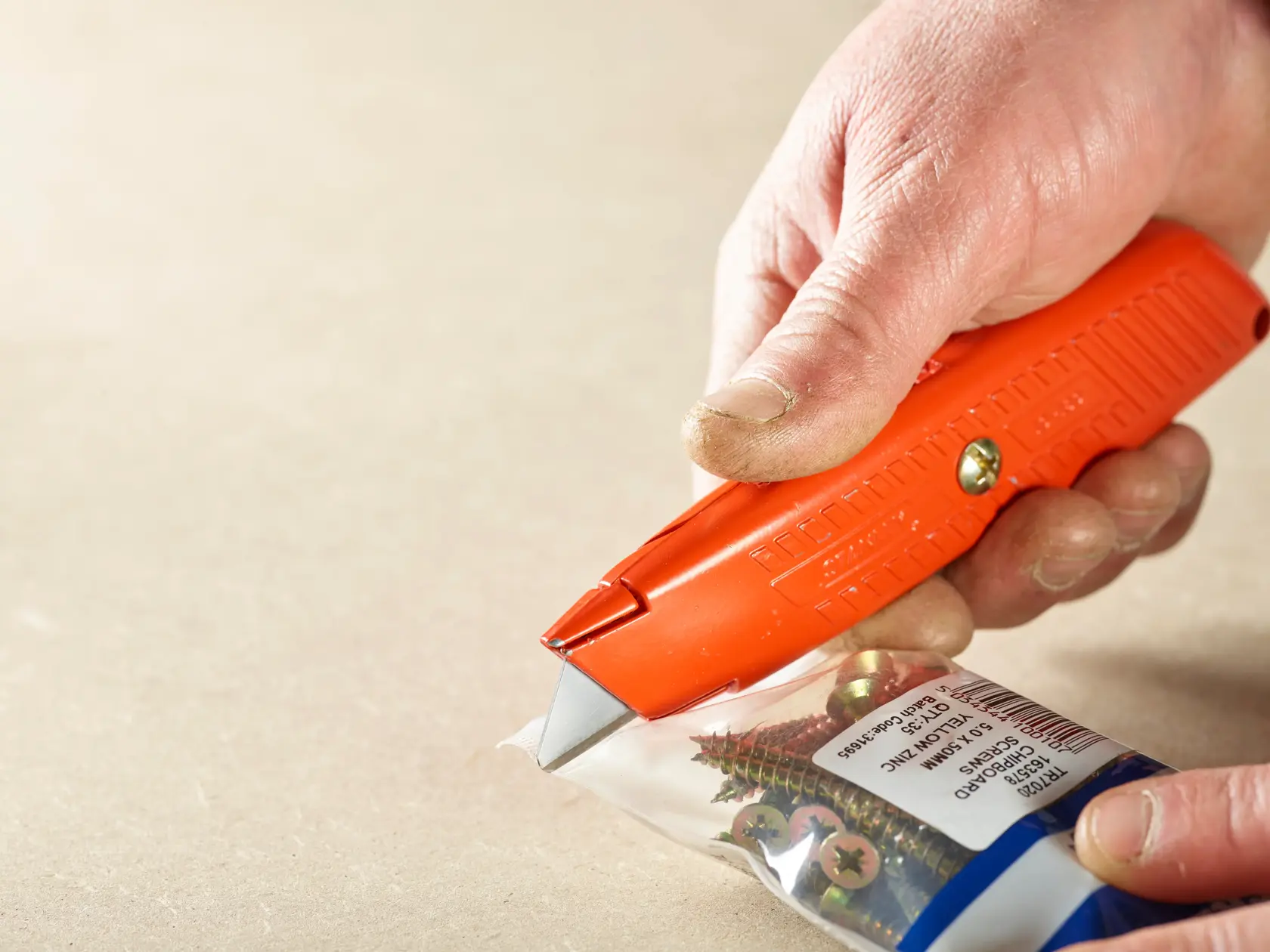 STANLEY 1-10-189 utility knife cutting open a bag of screws, close-up in use.