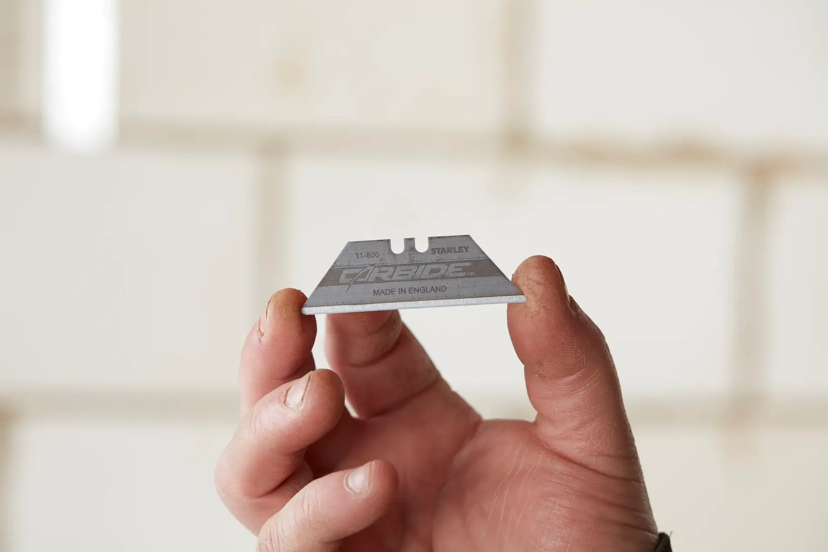 Photo of STANLEY 2-11-800 carbide utility blade held in a hand, product close-up, photography category.