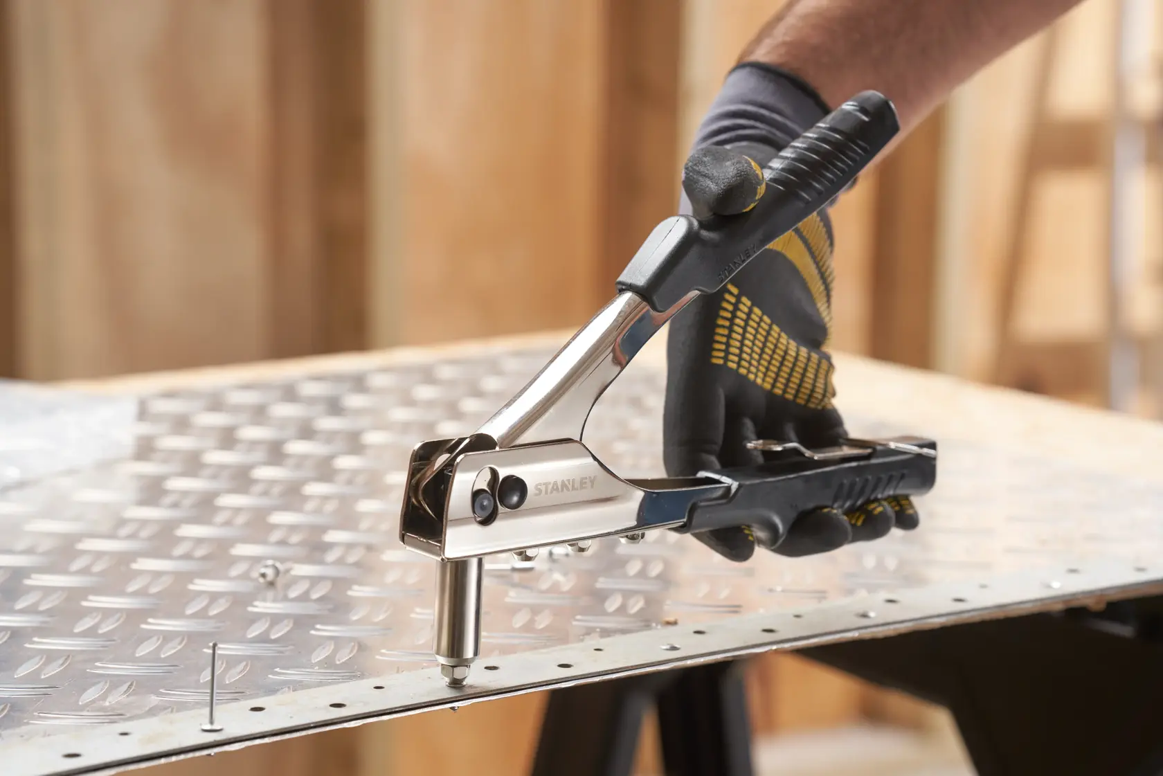 Photo of STANLEY 6-MR55 hand riveter tool being used on a metal sheet in a workshop.
