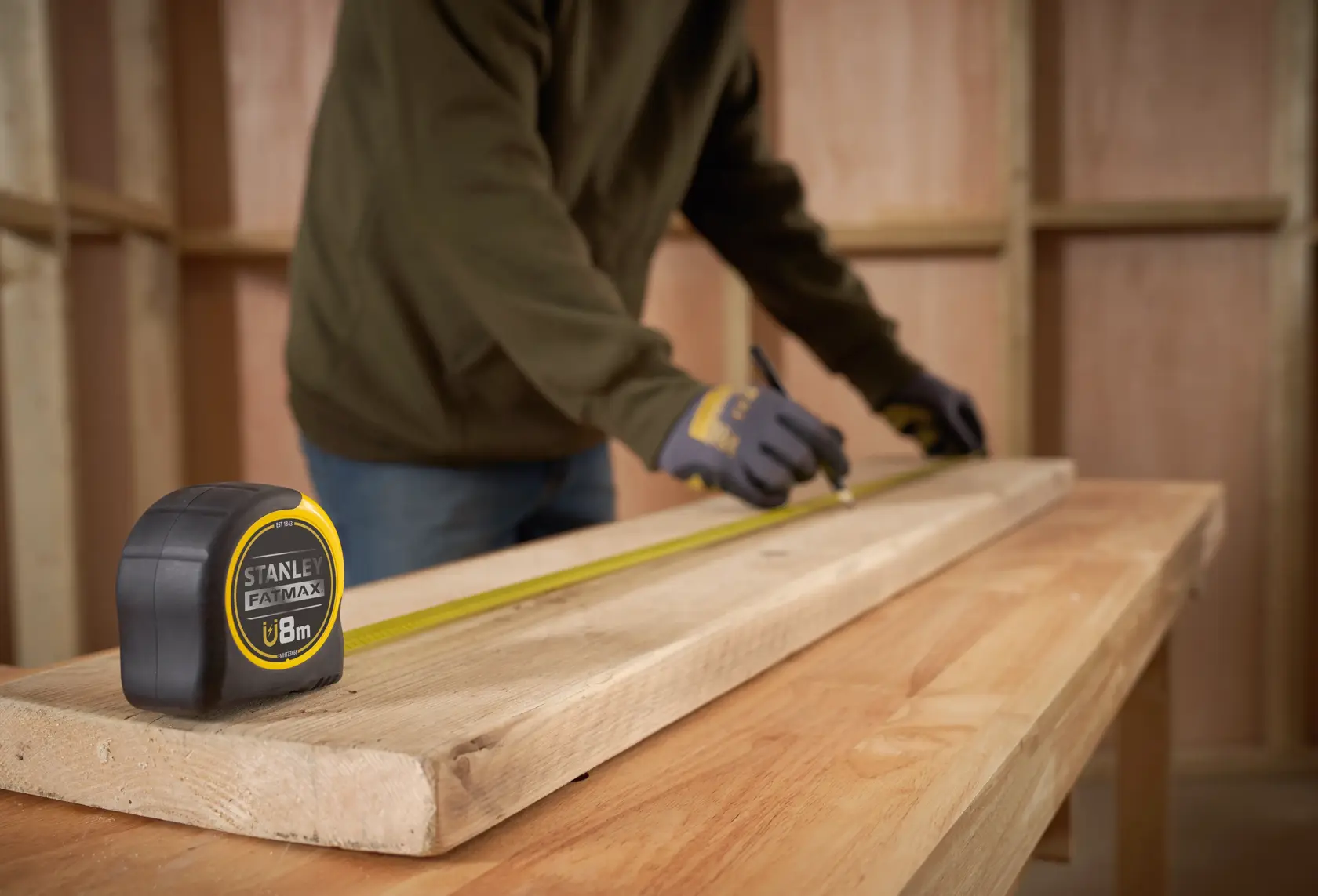 STANLEY FMHT0-33868 FATMAX tape measure on wooden beam in workshop, person marking measurements.
