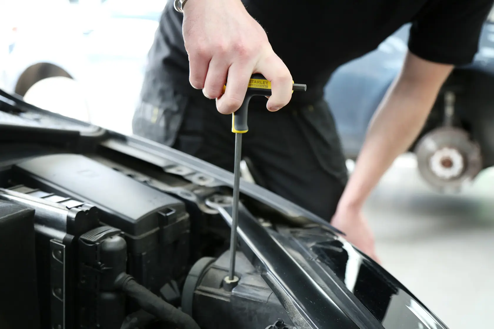 Photo of STANLEY FMHT0-69049 T-handle screwdriver in use on car engine, close-up view.