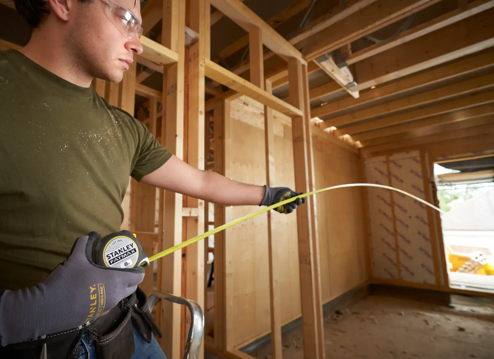 STANLEY FMHT38217-0 tape measure held by gloved hand in building construction setting.