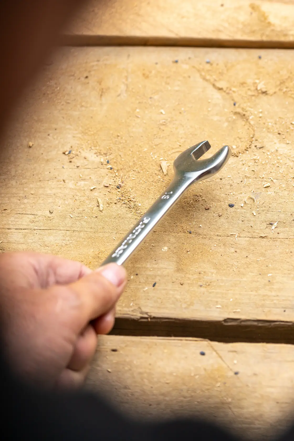 STANLEY FMMT13035-0 open-end wrench held on a wooden surface, silver metal finish.