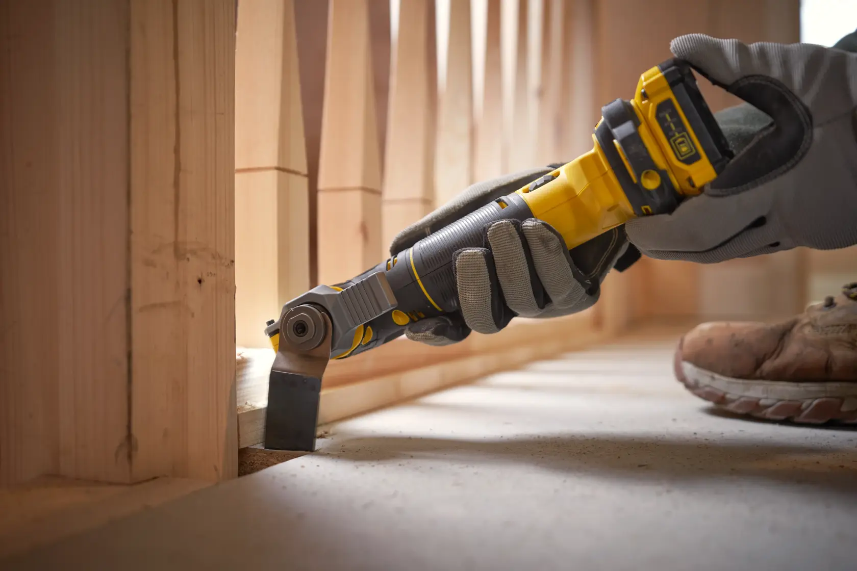 STANLEY SFMCE500D1K oscillating tool used for wood cutting near floor, close-up photography.