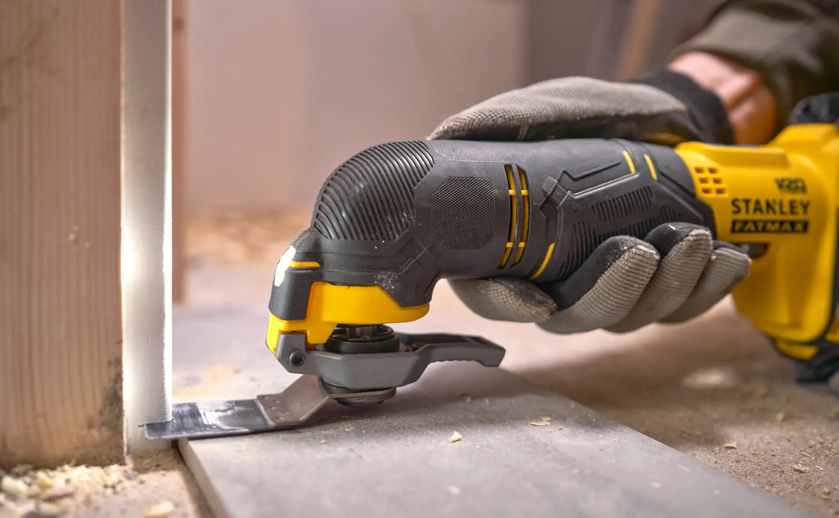 Stanley SFMCE500M1K oscillating multi-tool cutting wood at construction site, close-up view.