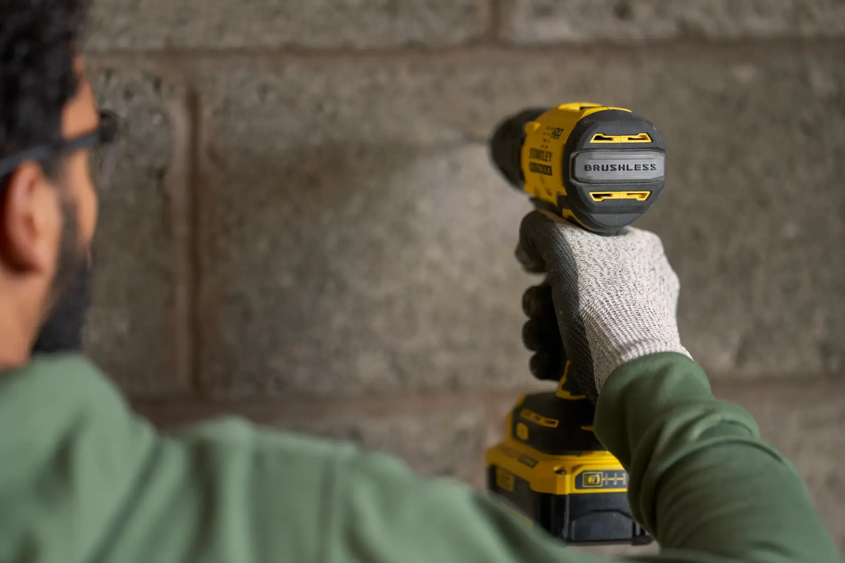 STANLEY SFMCK461M2S brushless cordless drill in use, shown close up drilling into concrete wall.