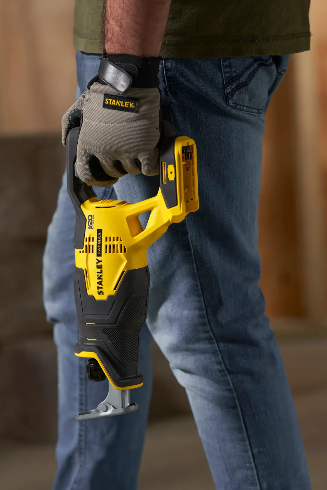 Photo of STANLEY SFMCS300M1K cordless reciprocating saw in yellow and black, held by a person wearing work gloves.