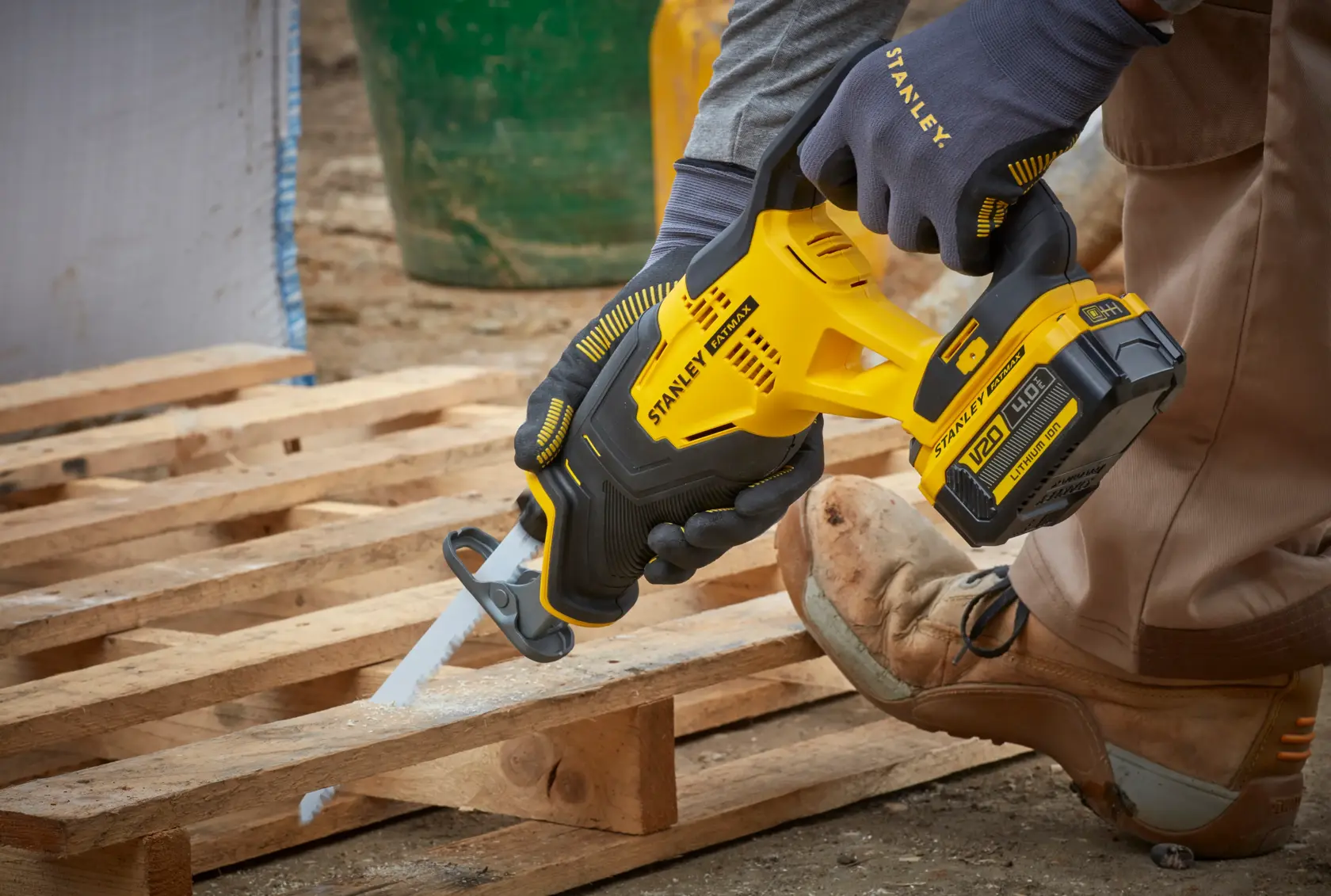 STANLEY SFMCS300M1K reciprocating saw in use, yellow and black, cutting wood pallet outdoors.