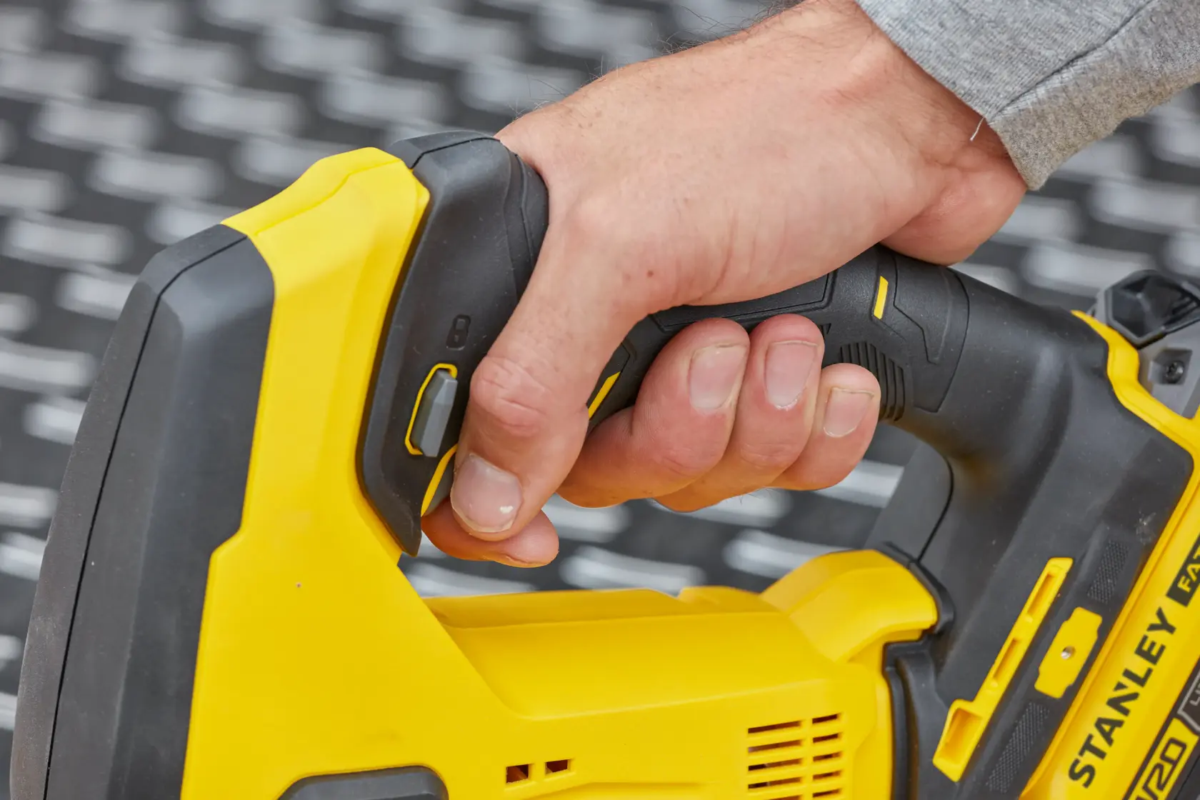 STANLEY SFMCS600M1K jigsaw close-up, yellow and black handle being gripped by a hand.
