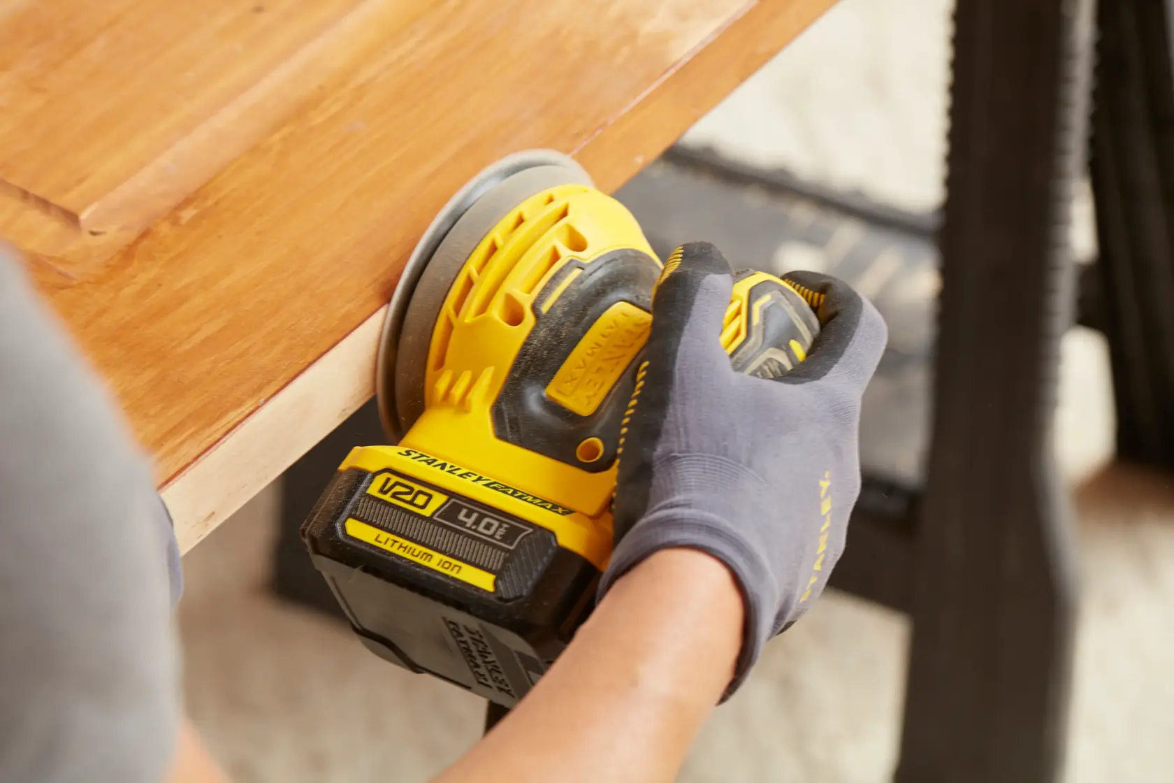 Photo of STANLEY SFMCW220M1S cordless sander in use sanding wooden surface.