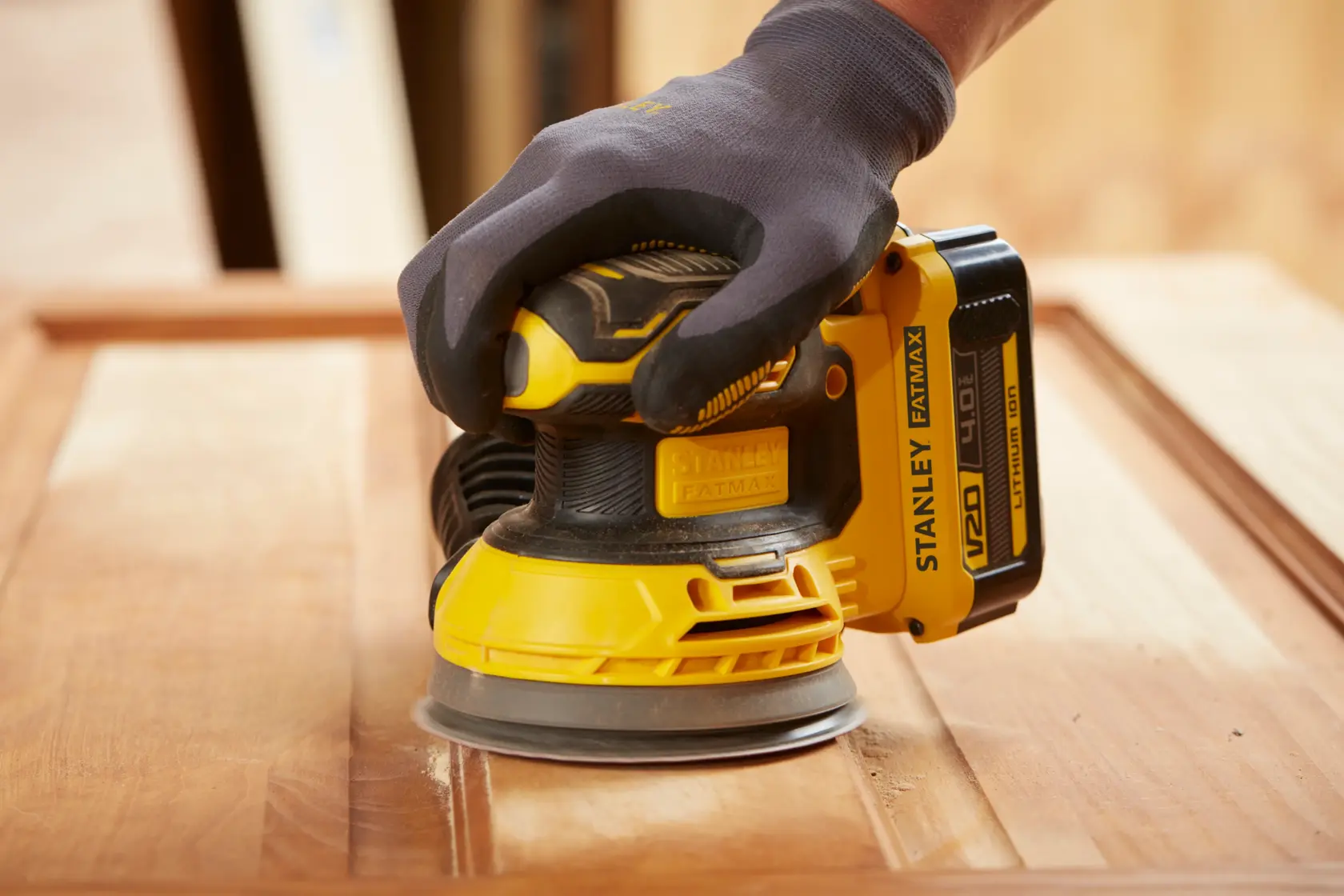 Photo of STANLEY SFMCW220M1S cordless sander in use on wooden surface, close-up angle.