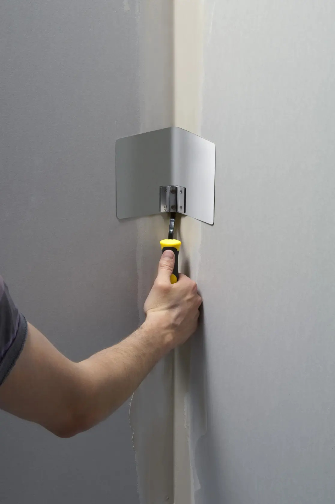 STANLEY STHT0-05777 corner finishing tool with yellow handle used to smooth joint compound in a wall corner.