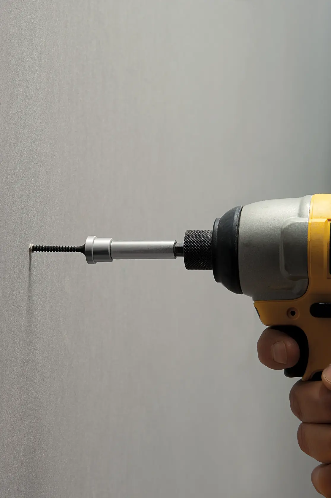 STANLEY STHT0-16137 screwdriver bit in drill driving screw into wall, side view.