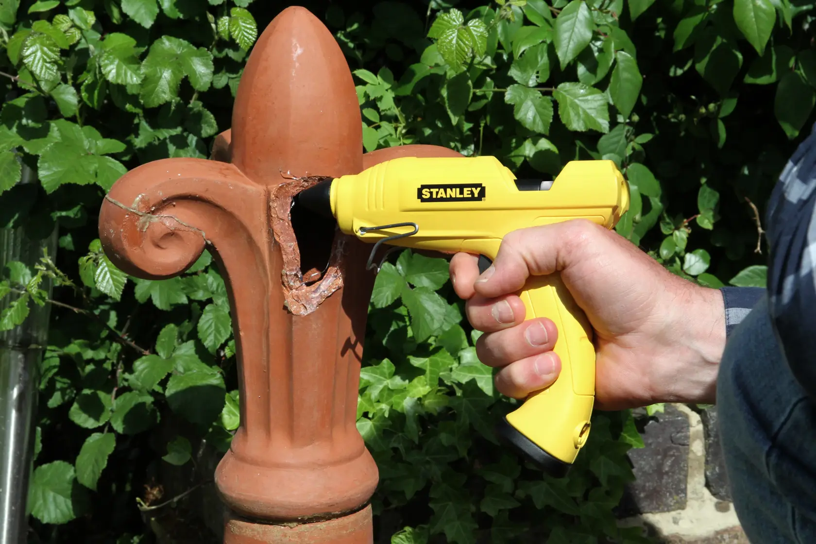 Photo of STANLEY STHT0-70416 yellow glue gun repairing ceramic outdoors.