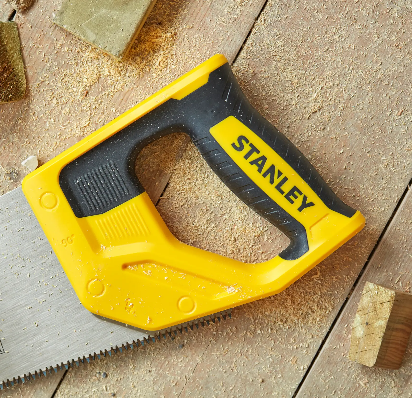 STANLEY STHT20350-1 hand saw with yellow and black handle, photography of saw on wood surface with sawdust.