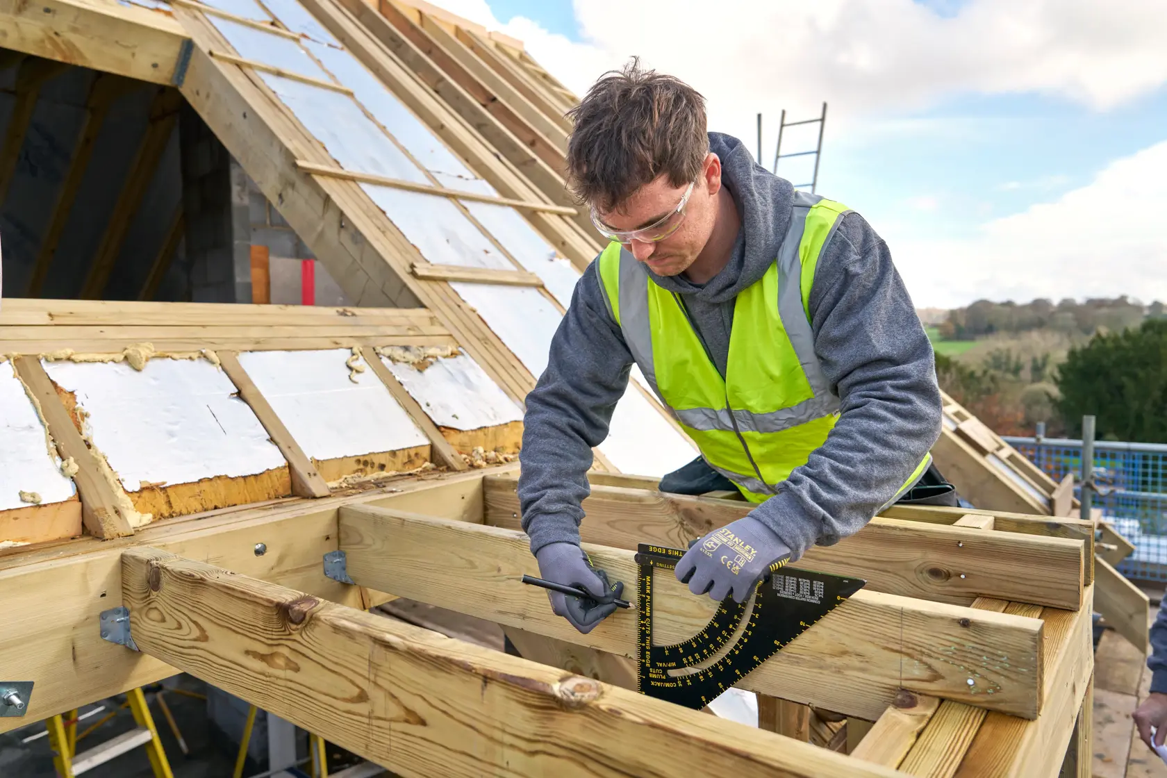 STANLEY STHT46055-0 roofing square used on wood frame during roof construction outdoors.