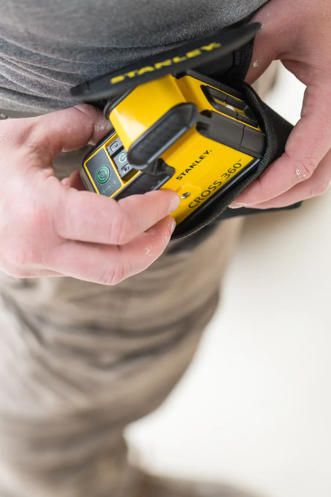 STANLEY STHT77594-1 yellow Cross 360 laser level held in hand with protective pouch.