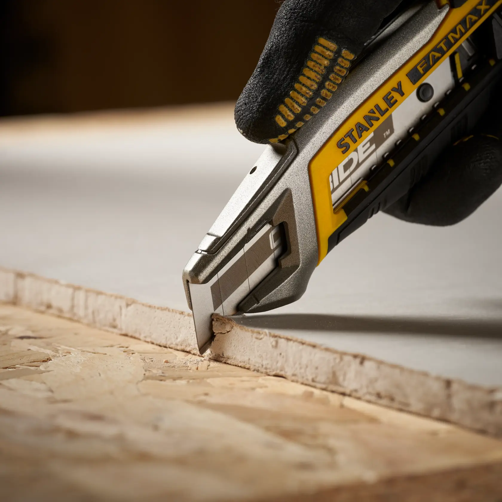Photo of STANLEY STHT8-11818 utility knife cutting drywall, close-up of blade and handle.