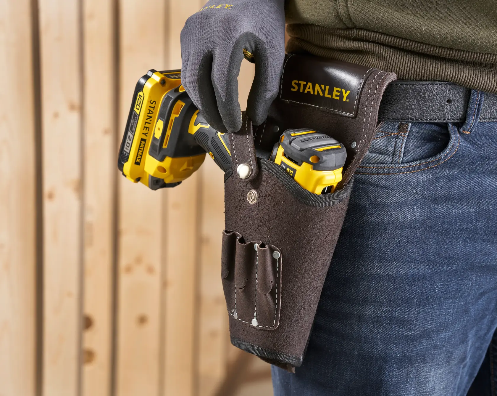 STANLEY STST1-80118 leather tool holster on belt, holding yellow power tools, close-up view.