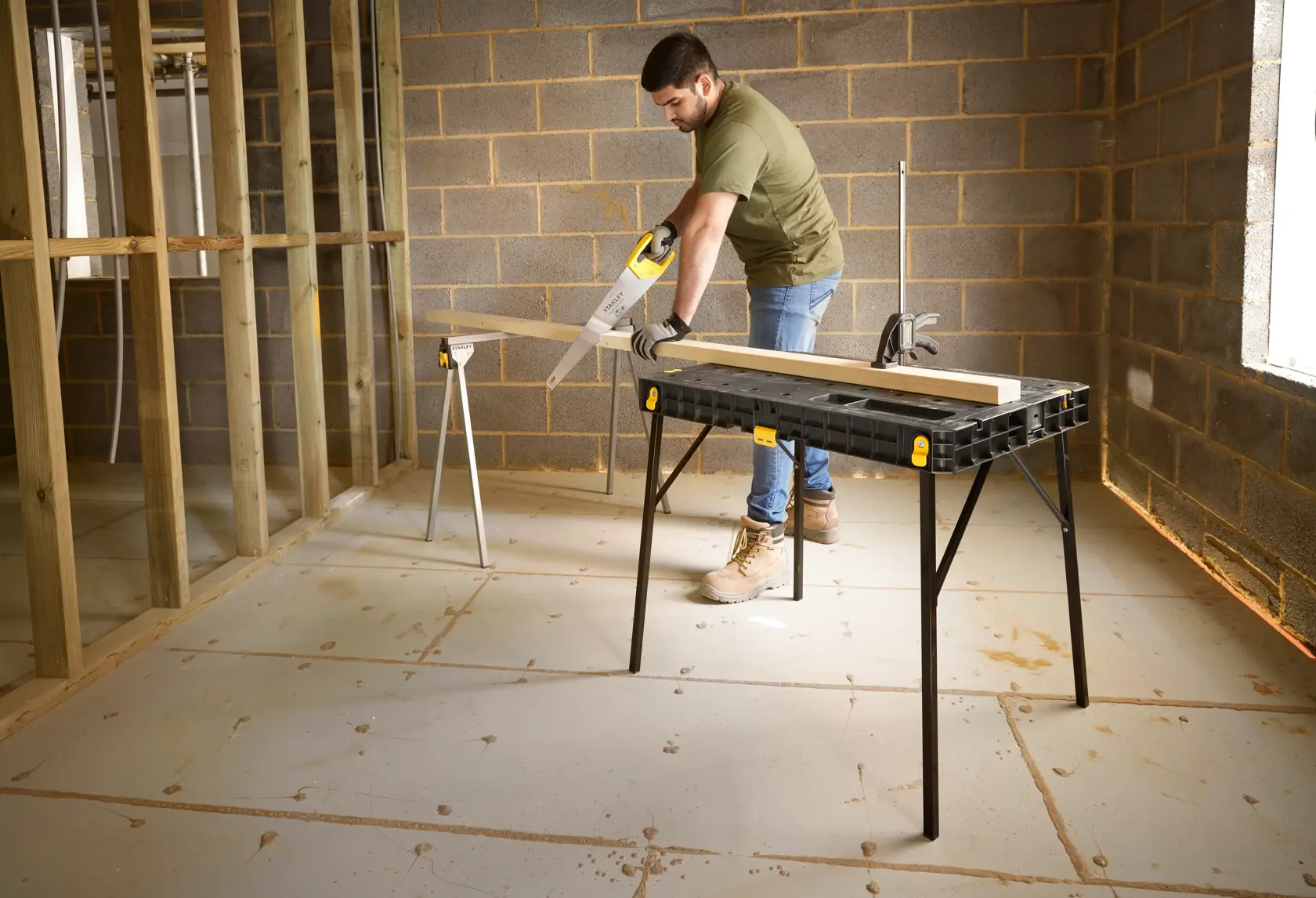 STANLEY STST83492-1 workbench table, black plastic top with yellow accents, used in construction site.