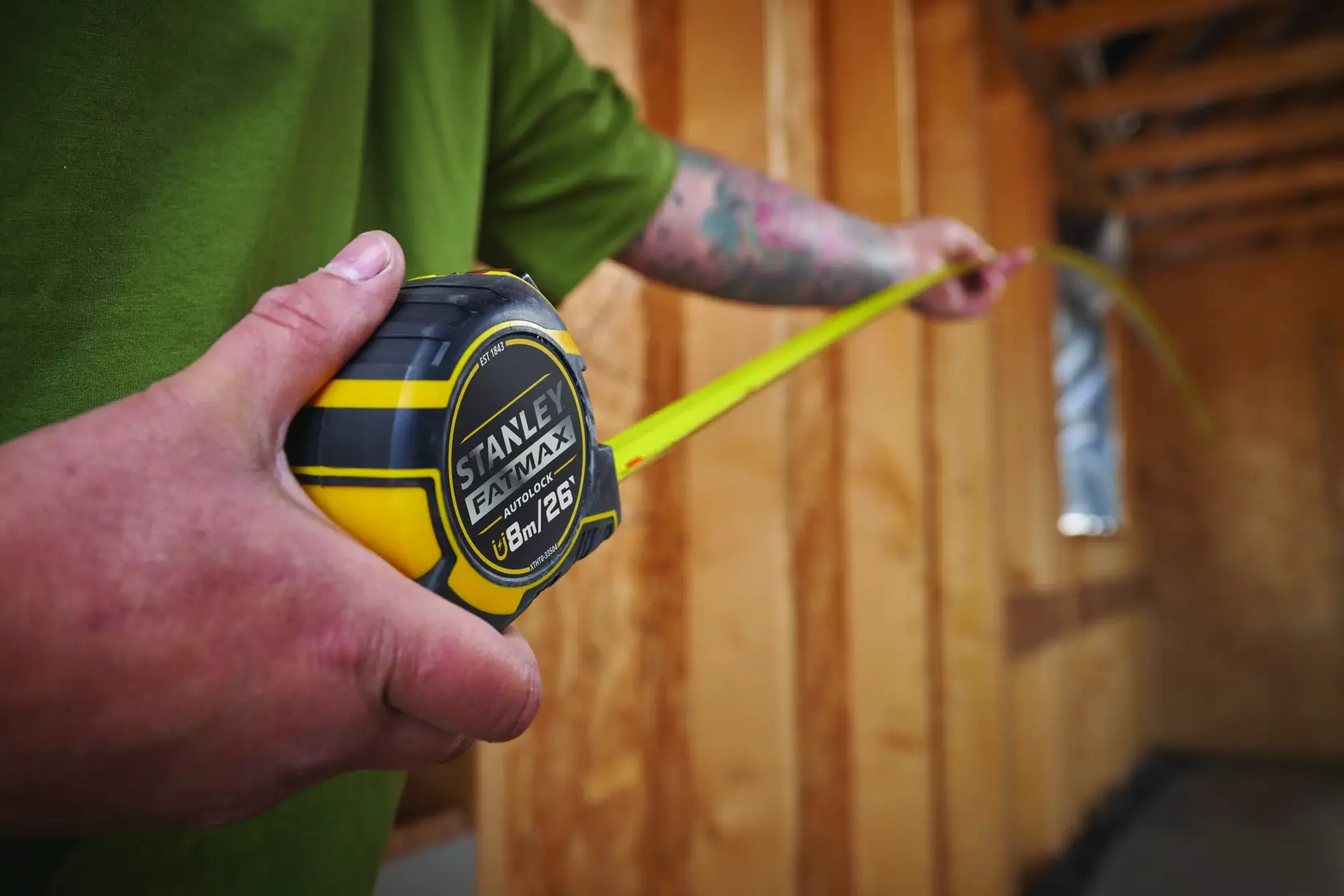 Photo of STANLEY XTHT0-33504 tape measure, 8m/26ft, in use at a construction site.
